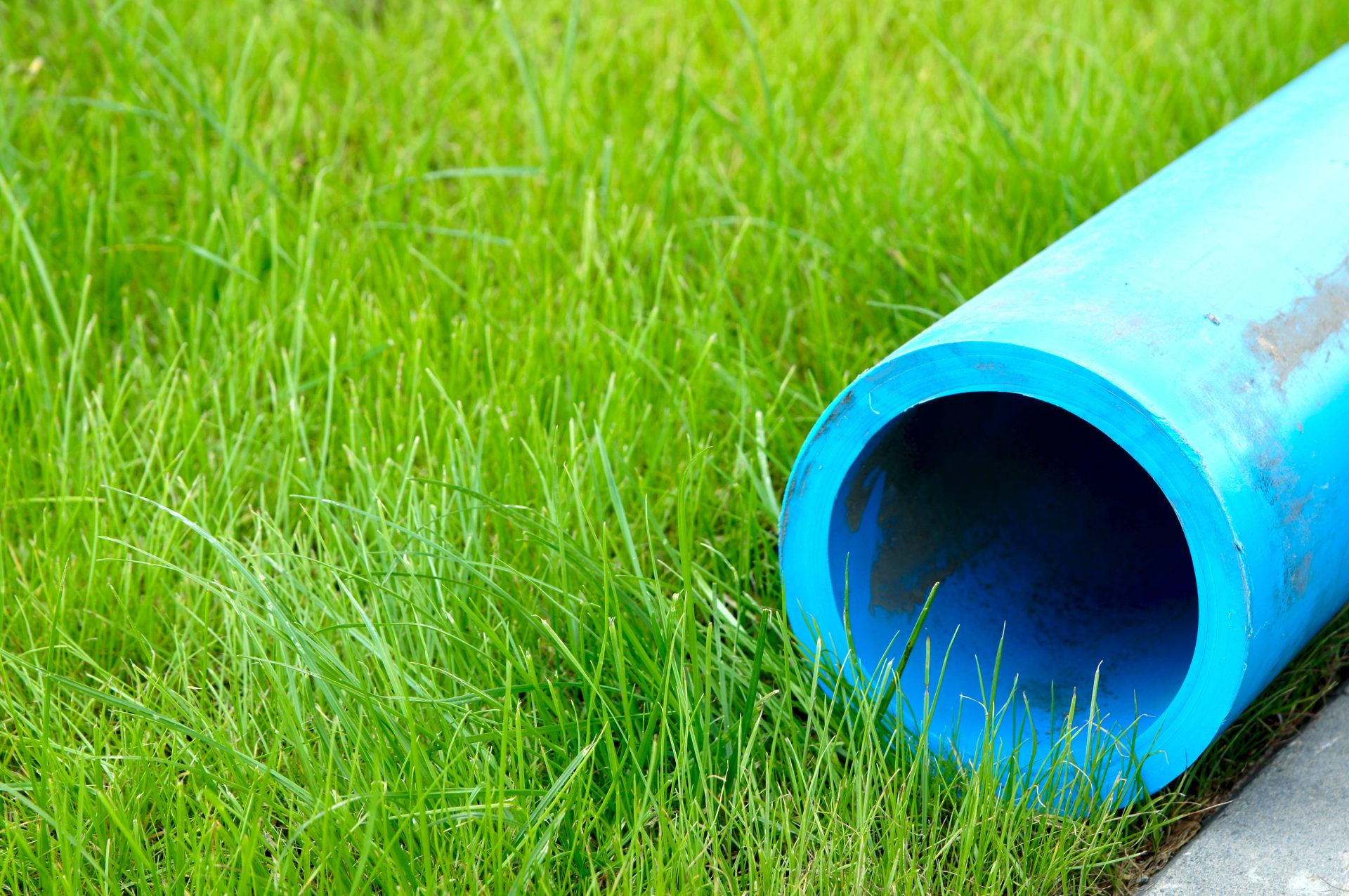 Large blue water pipe against green grass