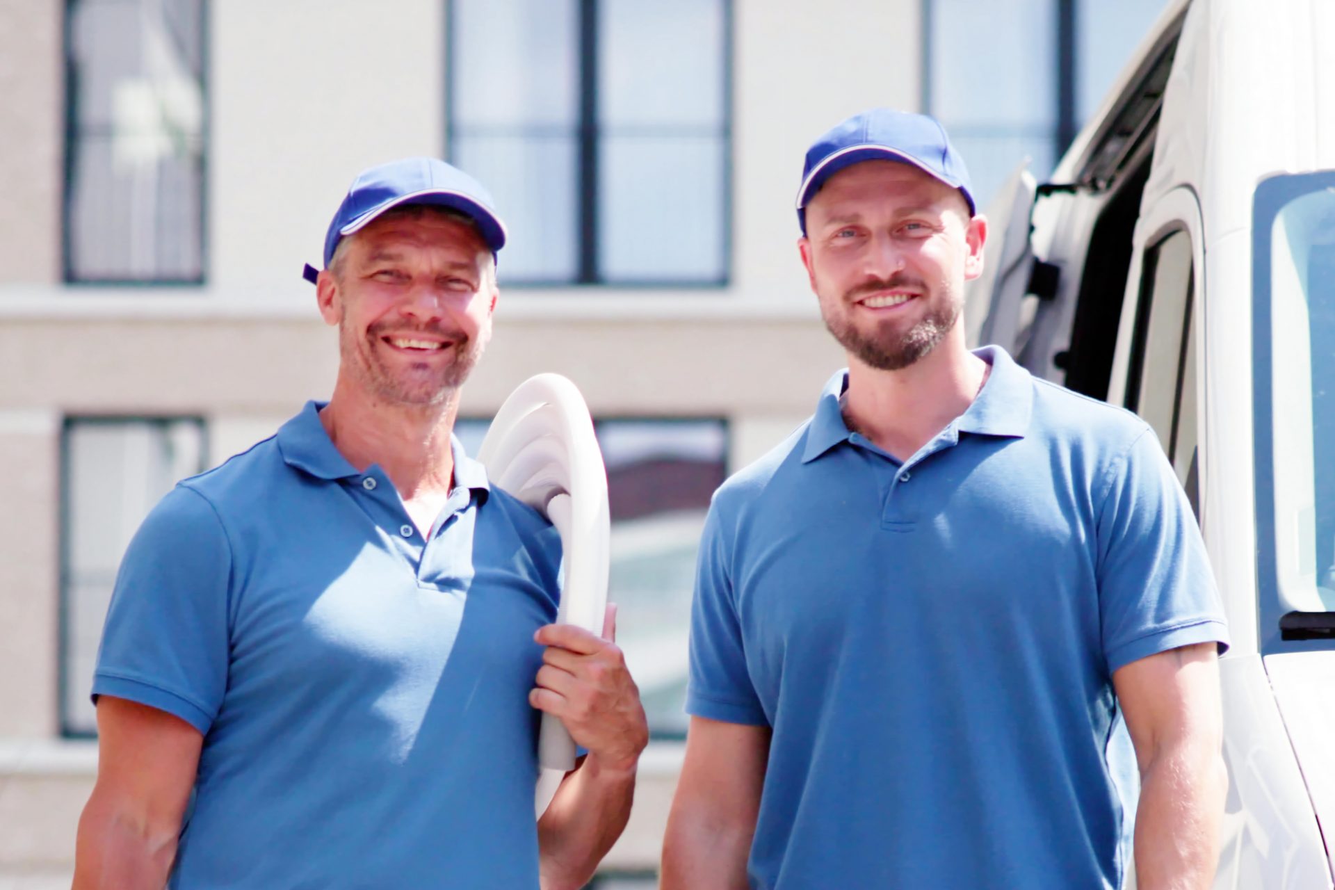 Two friendly male plumbers in blue shirts