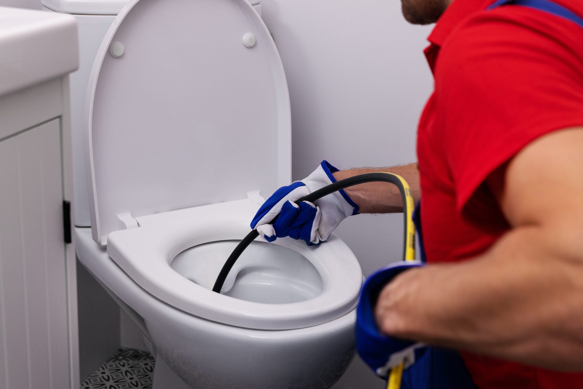 Plumber unclogging a toilet using hydro jetter