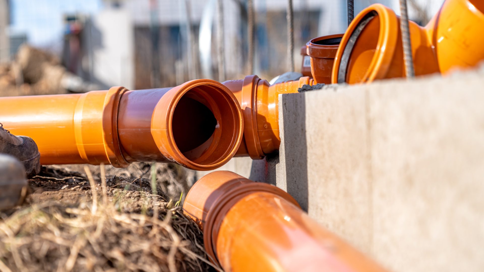 Orange PVC sewer line laying on ground of new sewer installation project