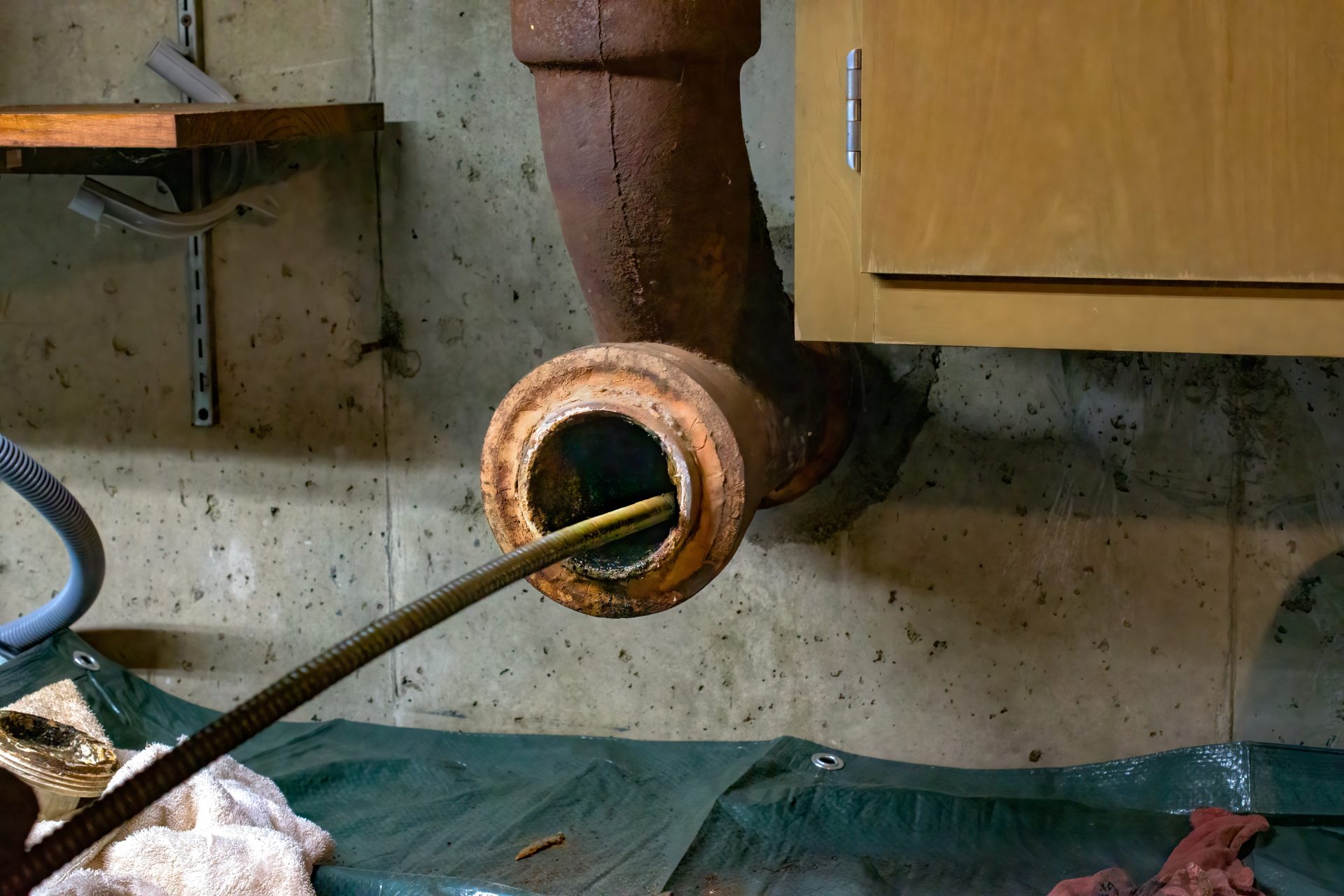 Plumber Pushing Rooter Tool Into Drain Line