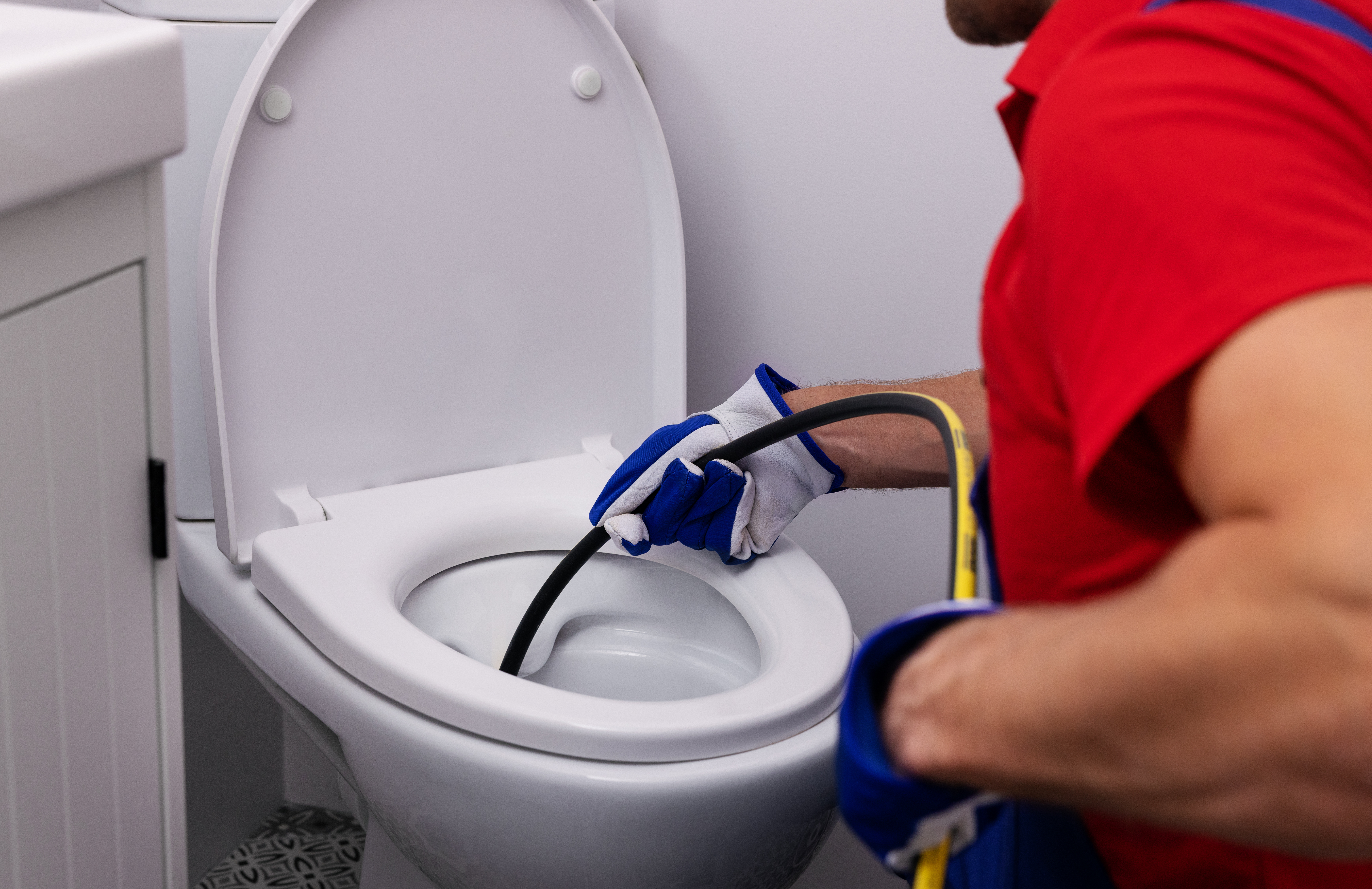 Worker Putting Line Down Toilet To Find Obstruction In Line