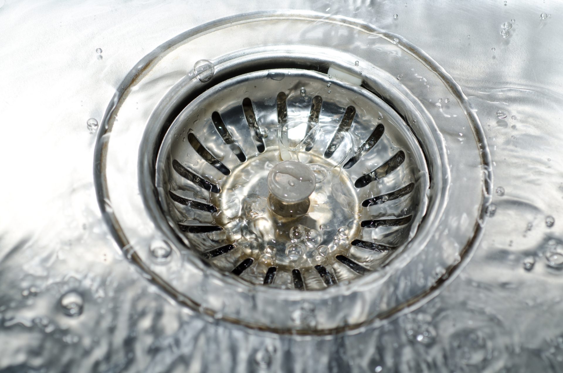 A kitchen sink drain with water flowing freely down it.