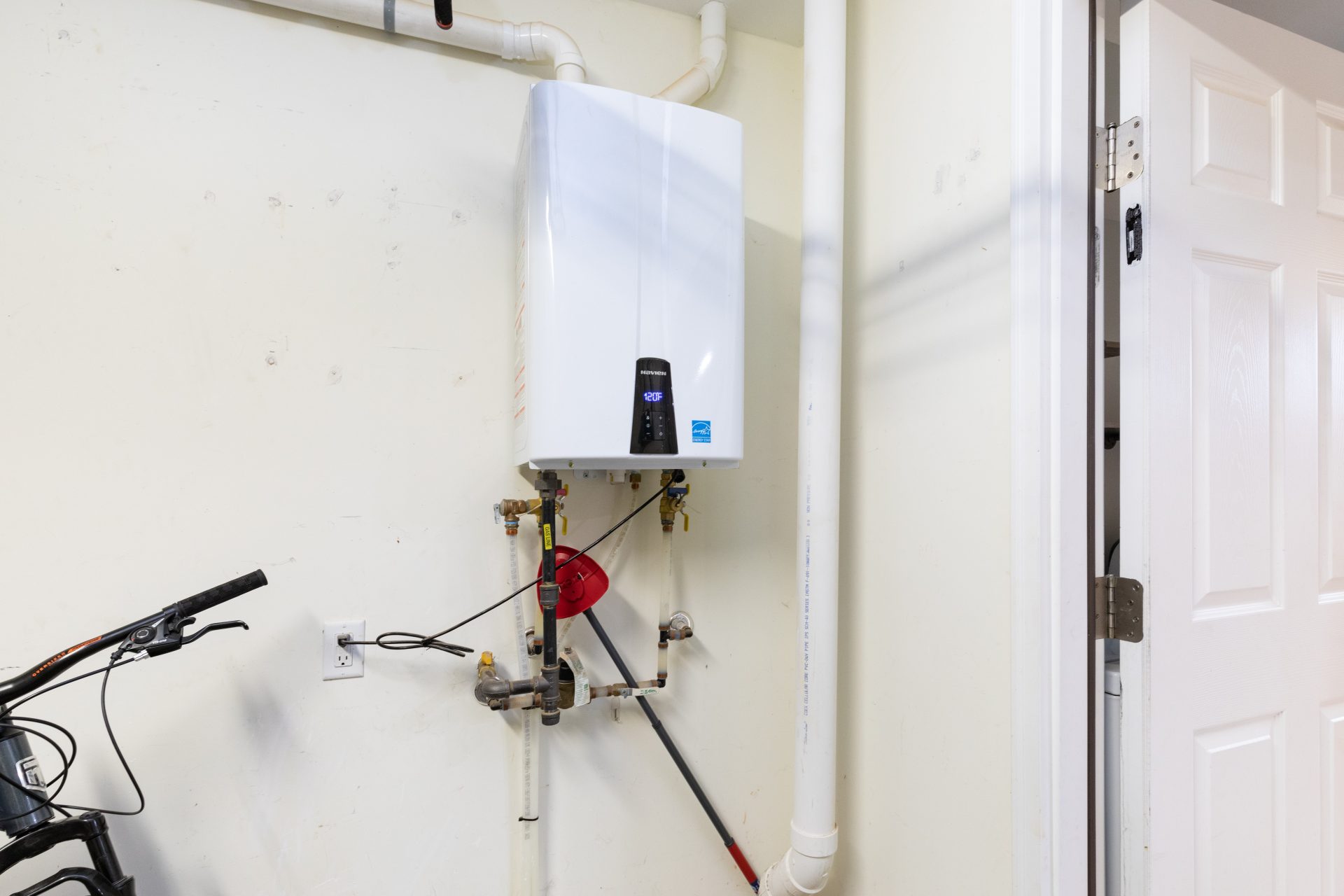 A tankless water heater mounted next to a bicycle.