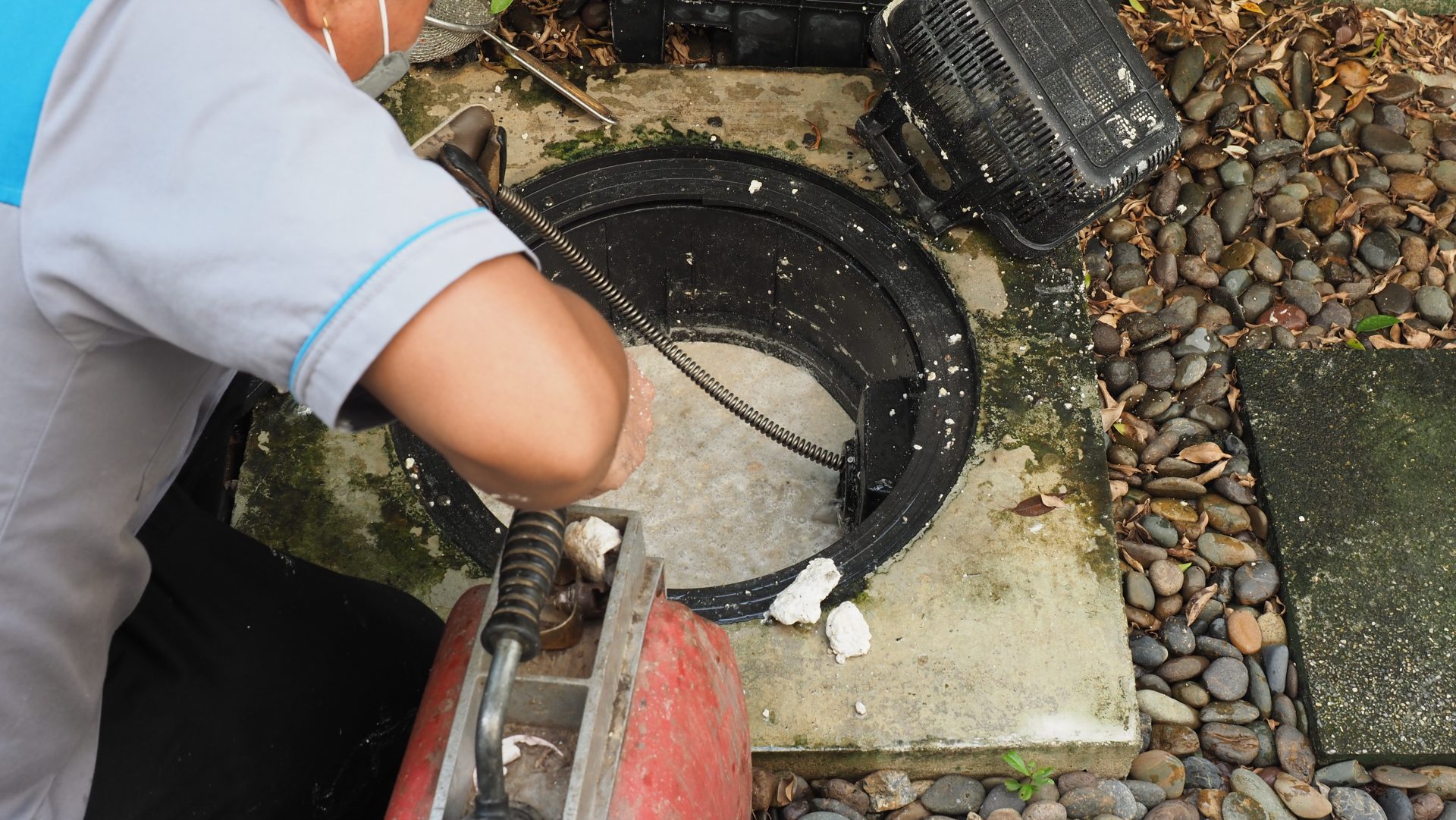 A plumber cleaning a residential drain.