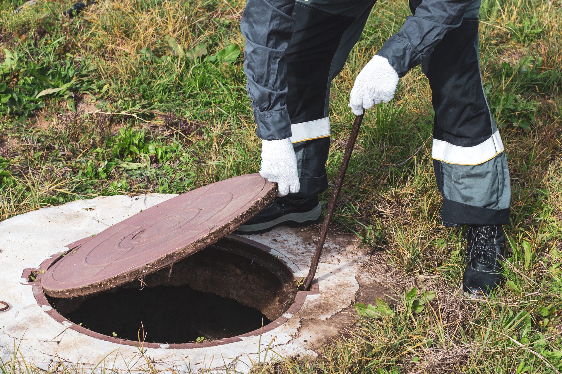 A technician opening a sewer cover to begin work.