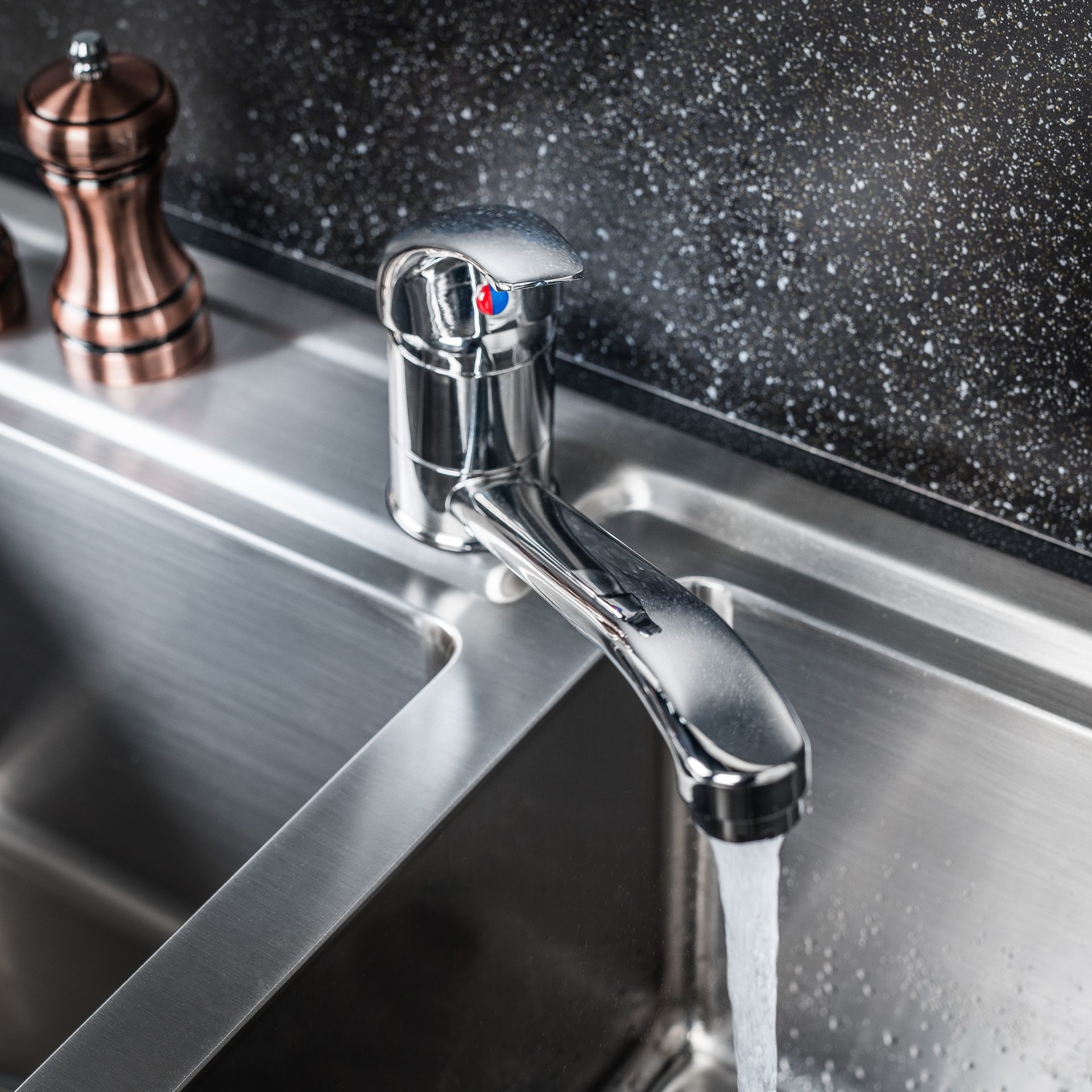 Fascinating Plumbing & Rooter Services In East Sonora, CA | Avalon Rooter A close-up of someone's hands adjusting plastic piping beneath a sink. There are multiple pipes and accordion tubes connected to promote the proper flow of water.