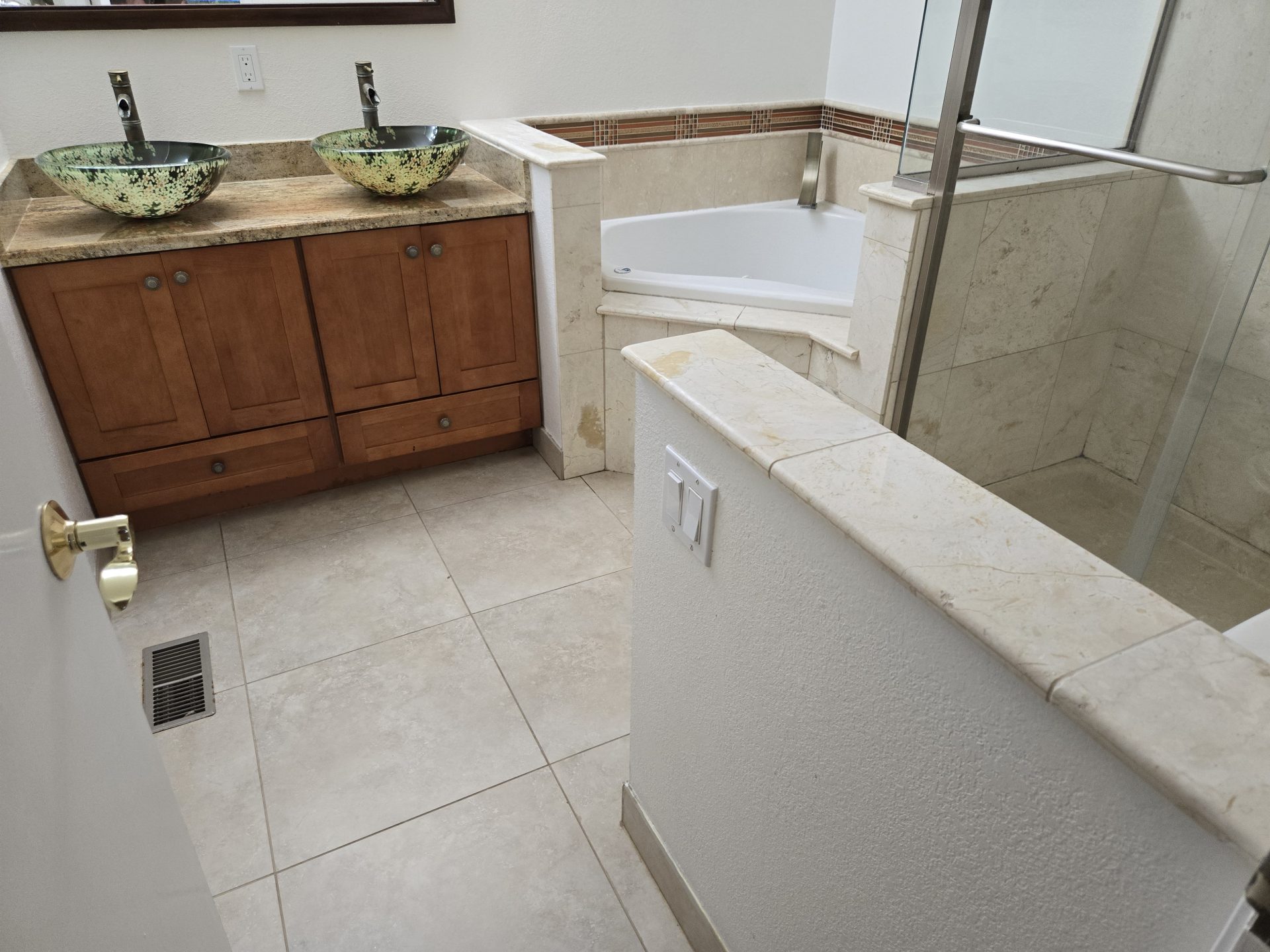 A modern residential bathroom featuring vessel sinks, a corner soaking tub, and a tiled shower showcases the results of professional plumbing & rooter services.